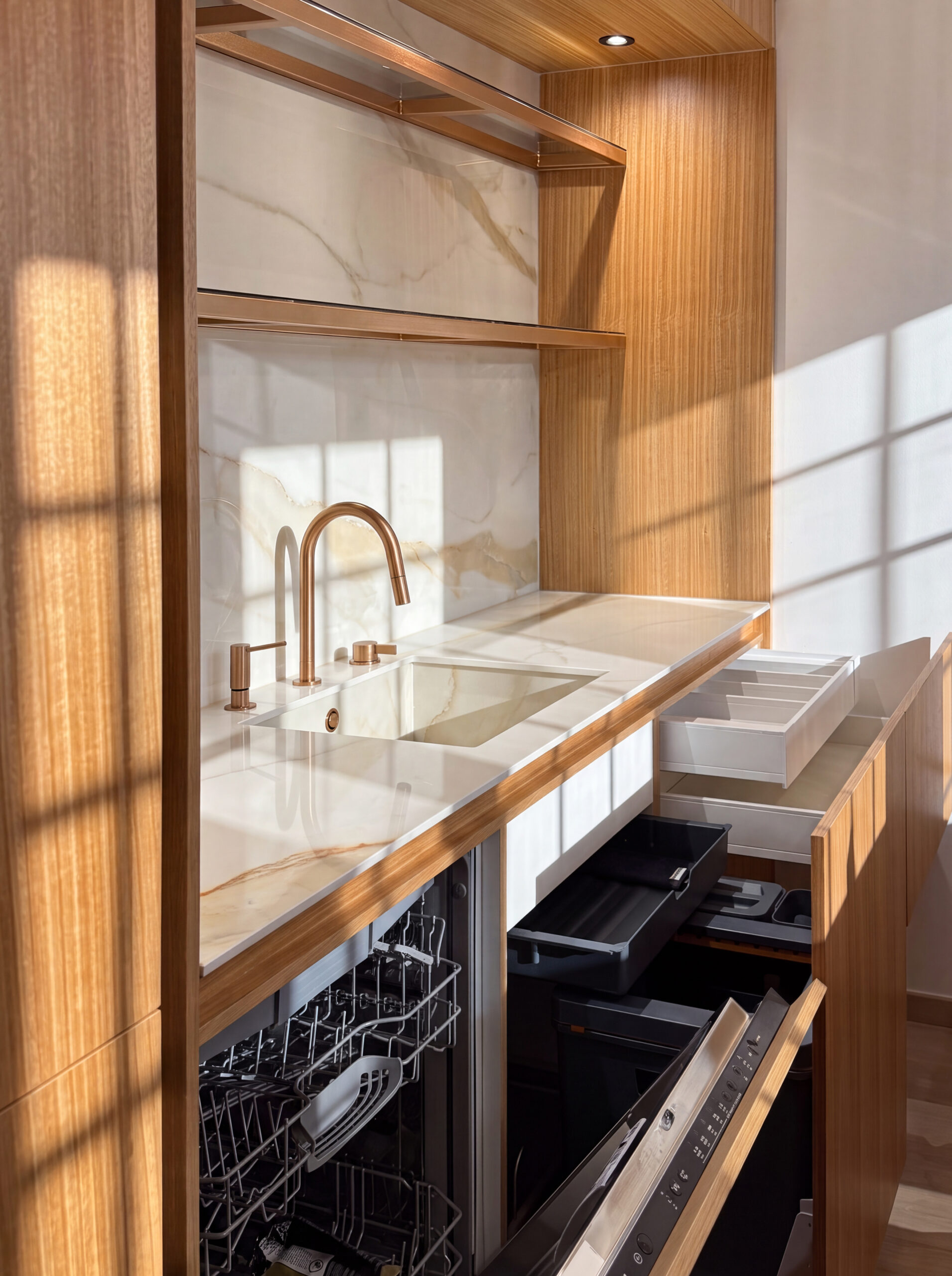 Coin évier en niche, plan et crédence en pierre claire, façades bois