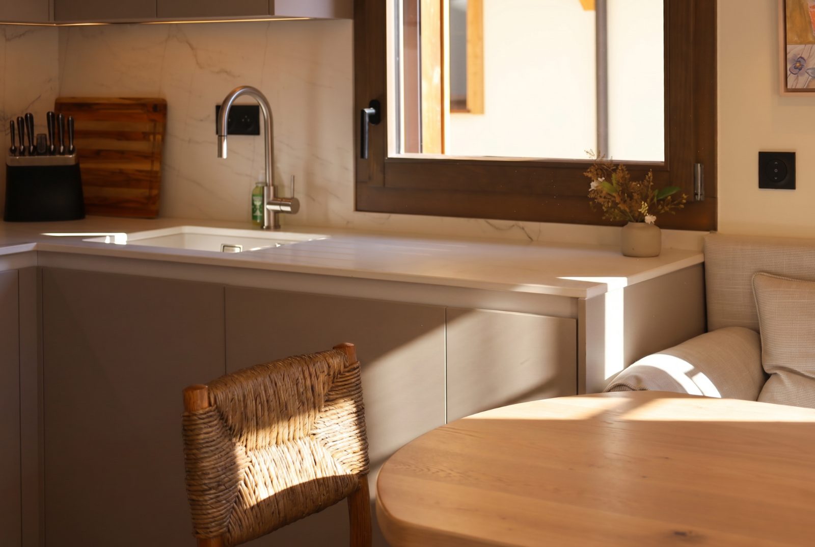 Évier sous plan dans un plan de travail clair, à côté d'une banquette et d'une table en bois